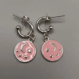 Aros de plata de ley con estrellas y luna en relieve sobre fondo en color rosa,