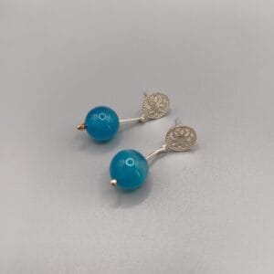 Pendientes en plata de ley montados con un roseton calado, palillo articulado y agata natural color azul